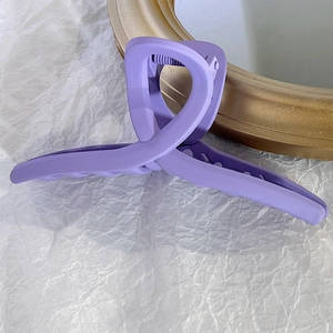 Détail d'une grande pince à cheveux violette mate avec design croisé et ressort en métal