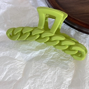Detail of neon green chain hair claw clip with matte finish on white textured paper