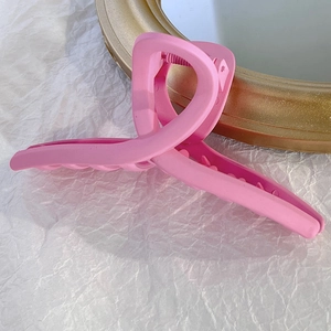 Gros plan d'une pince à cheveux rose mat au design torsadé pour cheveux épais