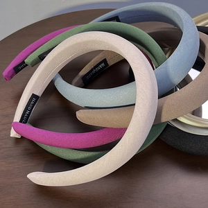 Detail of stacked handmade padded headbands showing fabric texture and woven brand label