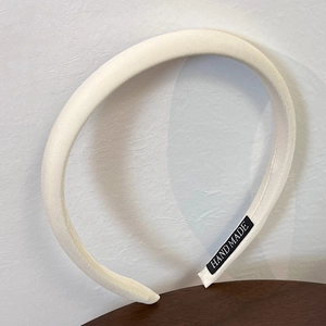 Detail showing cream padded headband texture with a black Handmade woven label