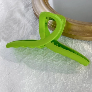 Détail de la pince à cheveux vert néon mat montrant les dents internes pour cheveux