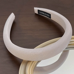 Detail shot of a thick sponge headband with a beige ribbed fabric and Hand Made label
