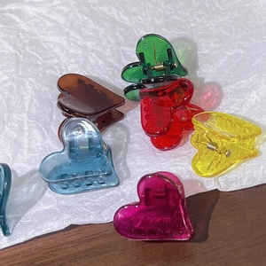 Gros plan de mini pinces à cheveux en forme de cœur, couleurs bonbon transparentes et ressort