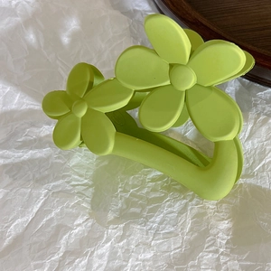 Close-up of matte avocado green hair claw clip with a stylish double flower design