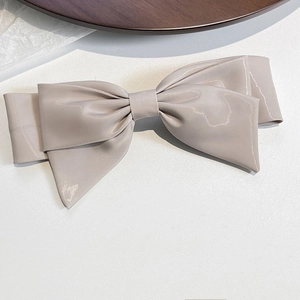 Detail view of champagne gold satin bow hair clip with elegant layered fabric texture