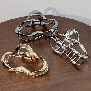 Elegant metallic cloud-shaped hair claws in gold, silver, and black on a wooden table