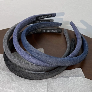 Close-up of three denim headbands in blue and black colors with a Hand Made fabric label