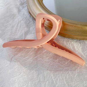 Gros plan d'une pince à cheveux mate rose abricot sur un tissu blanc froissé