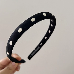 Détail d'un serre-tête rétro fait main en tissu noir à pois blancs de style français