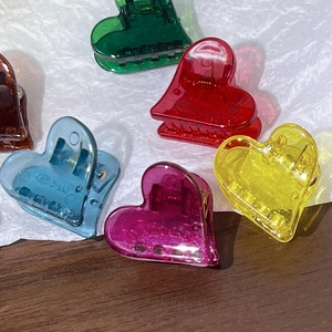 Vue macro de pinces à cheveux coeur colorées en teintes gelée translucides avec ressort