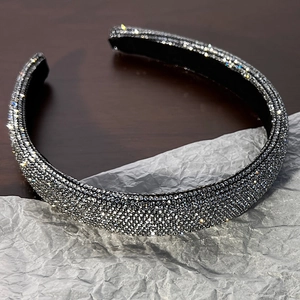 Dettaglio del cerchietto imbottito con strass grigi su sfondo scuro testurizzato