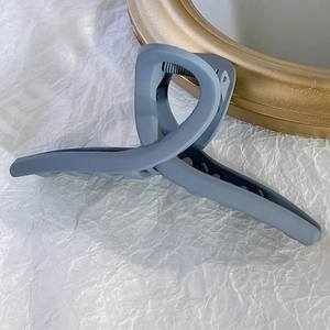 Détail de la pince à cheveux bleu gris mat sur fond de papier froissé blanc