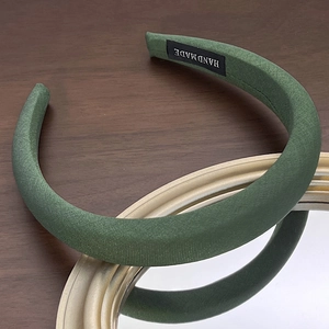 Detail of forest green padded headband with striped fabric texture and handmade tag