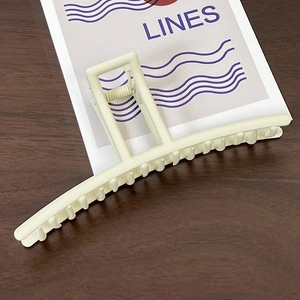 Detailed view of cream matte rectangle shark hair claw clip on wooden background