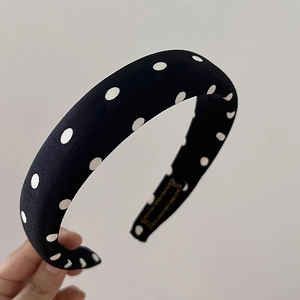Détail d'un serre-tête en éponge épaisse avec des pois blancs sur un tissu noir chic