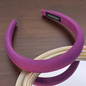 Detail of a purple padded sponge headband with handmade label on wooden surface