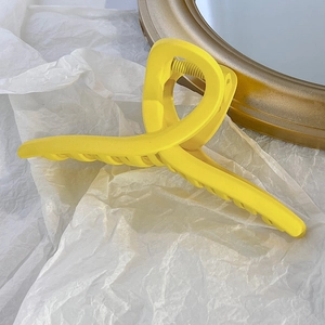 Détail de la pince à cheveux jaune mat avec design à dents croisées et ressort en métal