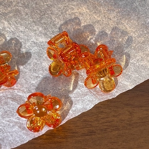 Macro shot of a mini orange translucent flower hair claw with a glossy resin finish