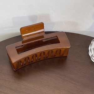 Makroaufnahme der großen bernsteinfarbenen Haarklammer mit glänzendem Finish und Hohlraumdesign