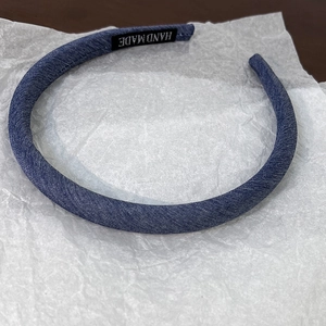 Detail of blue denim headband with black Hand Made woven label on the inner fabric band