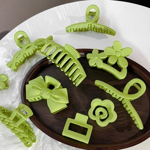 Assorted avocado green matte hair claws with bow and floral designs on wood tray