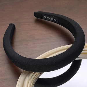 Macro detail of thick black sponge headband with a handmade label on dark wood texture