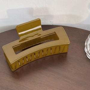 Detail der eleganten olivgrünen Haarklammer mit Spiegeleffekt auf einem Holztisch präsentiert
