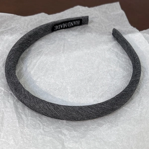 Detail view of a handmade grey textured headband featuring the HAND MADE artisan label