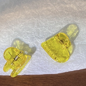 Gros plan de deux pinces à cheveux coeur jaune en acrylique sur un fond de bois brun