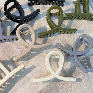 Minimalist large cross-wrap hair claws in assorted matte colors on textured paper