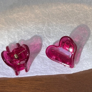 Détail de petites pinces à cheveux en forme de cœur magenta translucide avec ressort