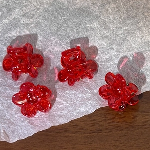 Detail view of mini red floral hair claws made of resin with sturdy metal springs