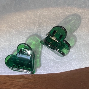 Détail de deux petites pinces à cheveux en forme de cœur vert bonbon en acrylique poli