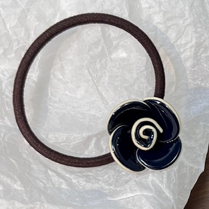 Detail of high-elasticity hair tie with glossy black and white resin camellia flower