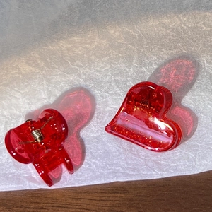 Détail de pinces à cheveux rouges en forme de cœur avec paillettes dorées et ressort