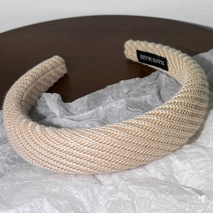 Gros plan sur le bandeau en tricot beige avec étiquette faite main et texture en spirale