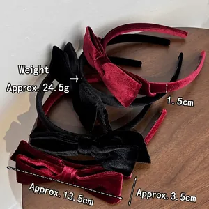 Elegant vintage velvet bow headband in black and burgundy on a natural wooden surface