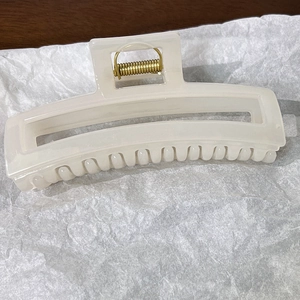 Vue détaillée de la pince à cheveux rectangulaire en résine crème avec ressort doré