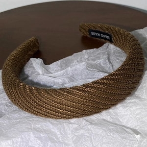 Détail du bandeau en tricot marron foncé avec étiquette fait main sur papier blanc