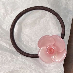 Detailed view of an elegant light pink camellia flower hair tie with glossy resin finish