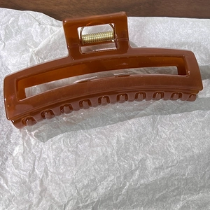 Détail d'une grande pince à cheveux rectangulaire ambre avec un design creux et poli