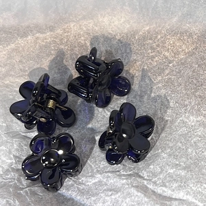 Detail view of four mini navy blue flower hair claws made of translucent acrylic