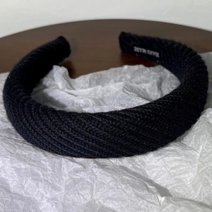 Détail d'un serre-tête en tricot noir avec étiquette fait main sur fond vintage