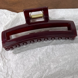 Détail d'une grande pince à cheveux rectangulaire bordeaux avec ressort doré