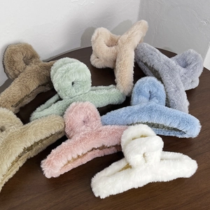 Detail showing multiple plush hair claws in various soft colors on a wooden surface