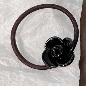 Detailed macro shot of a black resin rose charm on a coffee-colored elastic hair tie