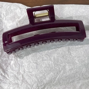 Détail macro d'une pince à cheveux rectangulaire violet foncé avec ressort doré