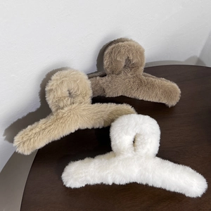 Three plush faux fur hair claws in white and brown shades on a rustic wooden desk