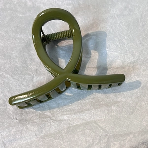 Olive green hair claw clip with glossy finish and modern crisscross design detail
